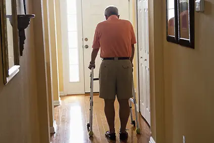 老人用助行器在家里走动。
