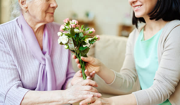 一位女士给她年长的母亲一束花。