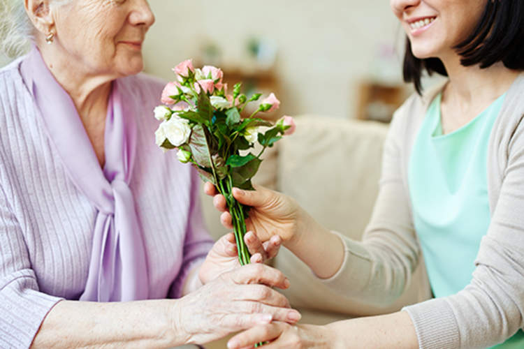 一位女士给她年长的母亲一束花。