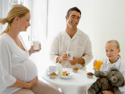 家庭吃用果汁，牛奶，松饼，咖啡和新鲜水果早餐。