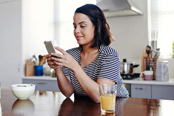 女人用她的智能手机在厨房里跟踪她RA症状。