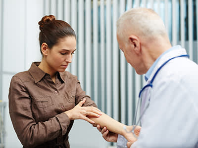 医生在检查一个女人手臂上的皮肤。