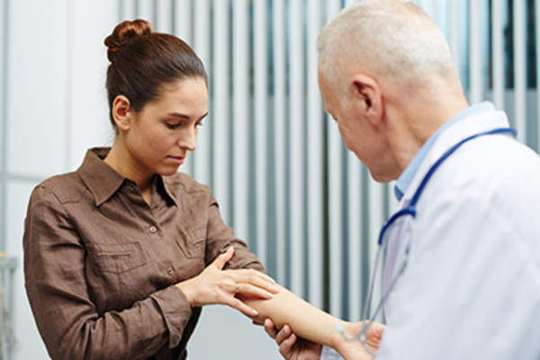 医生在检查一个女人手臂上的皮肤。