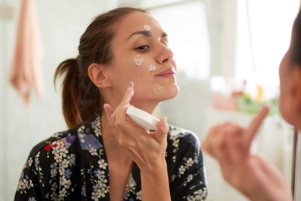 女人在脸上涂润肤膏