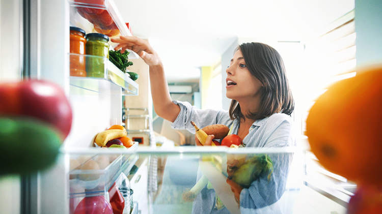 女人选择从冰箱里的水果和蔬菜。