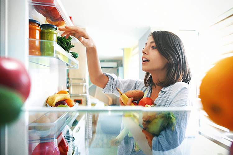 女人选择从冰箱里的水果和蔬菜。