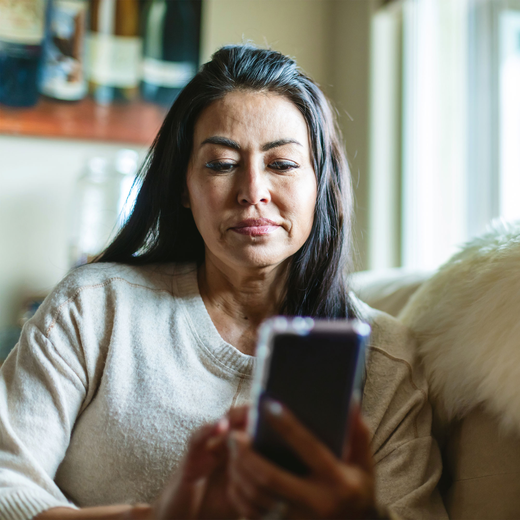一位女士在家里使用她的手机
