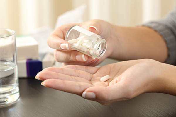 从瓶子里拿补品的女人。