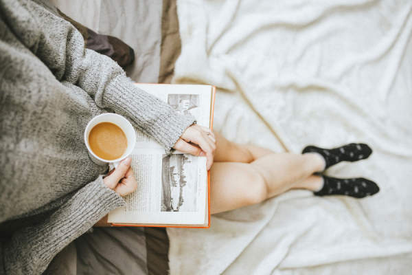女人在毛衣喝茶，在床上看书