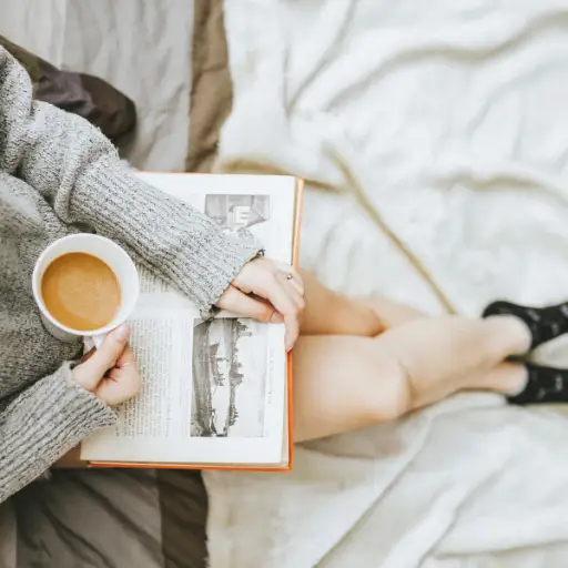 饮用的茶和阅读书的妇女在床上