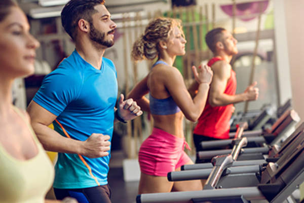 在健身房的跑步机上跑的年轻人群