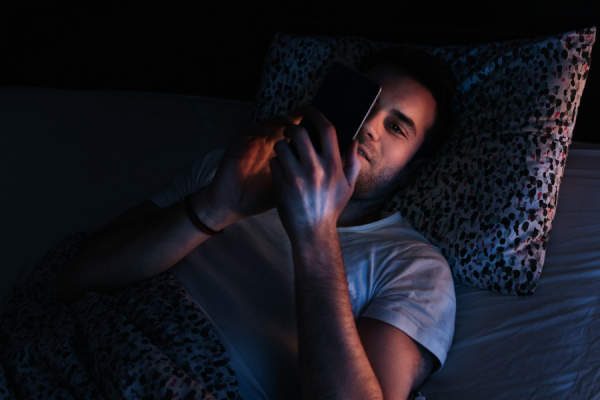 年轻人晚上在床上使用智能手机
