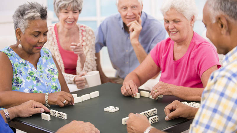一群老年人在玩多米诺骨牌。