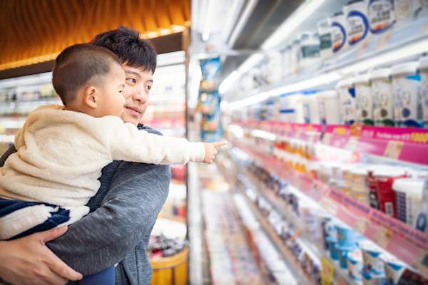 男人和他的儿子在奶制品通道买东西。