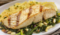 Grilled fish on top of greens.