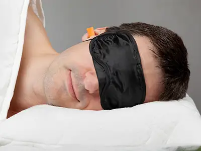 男人戴着眼罩和耳塞睡觉。