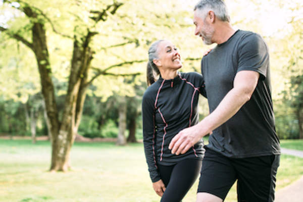 幸福的夫妇穿着运动服在公园散步和聊天。