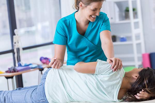 微笑与女性患者髋骨物理治疗工作。