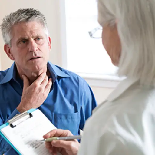 Man discussing throat pain with his doctor.