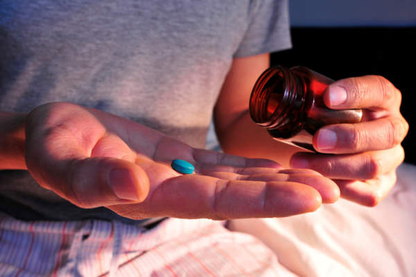 男人在床上吃蓝色药丸