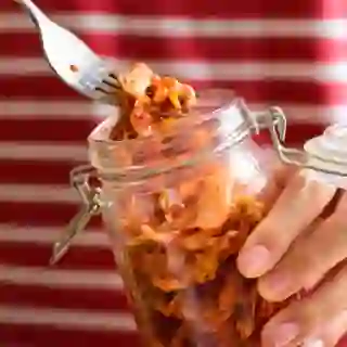 hands holding jar full of kimchi