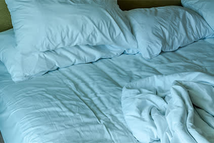 未整理的床上铺着蓝色的床单和旧床垫。