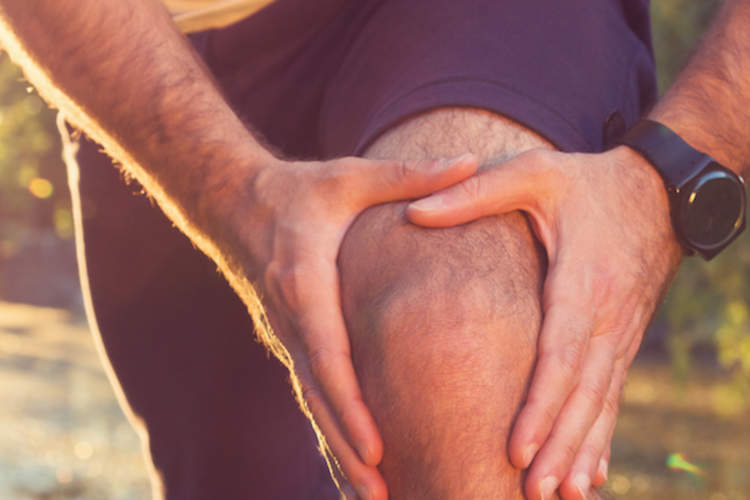 有膝关节疼痛的滑行停下来握住他的膝盖。