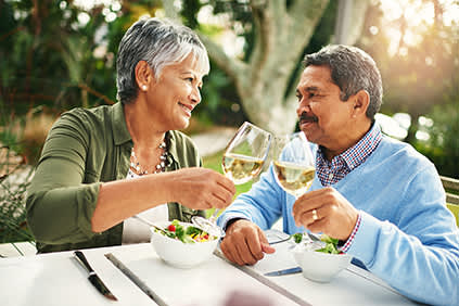 高级夫妇喝白葡萄酒与健康的沙拉。