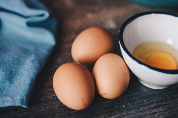 三个全棕色的鸡蛋放在碗里的碎鸡蛋旁边