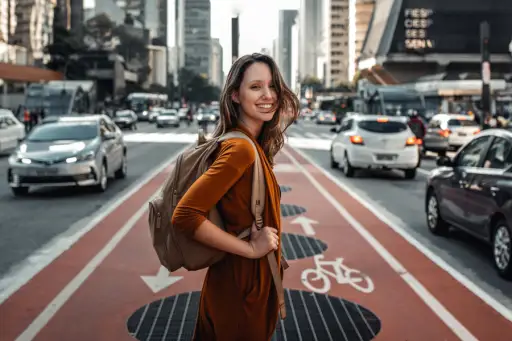 妇女微笑的佩带的背包在城市
