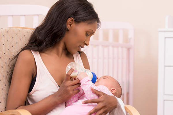 母亲奶瓶喂养新生儿的形象。