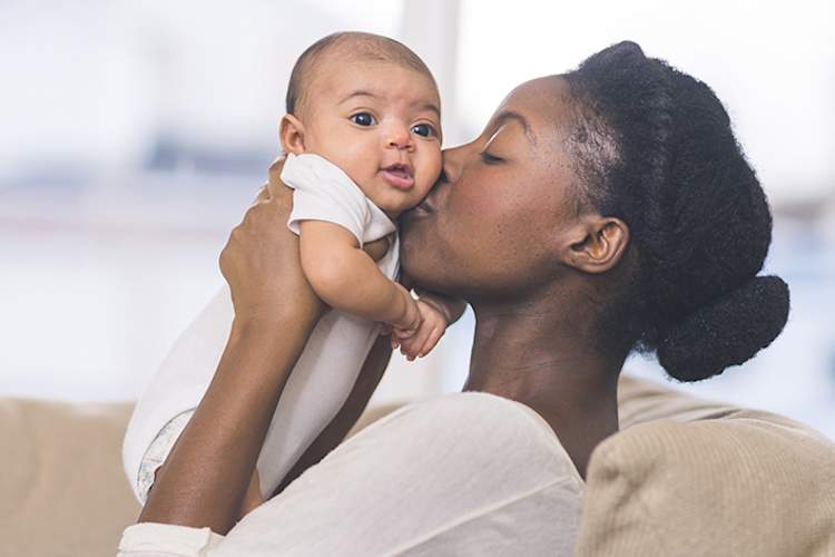 母亲抱着并亲吻着她快乐的孩子。