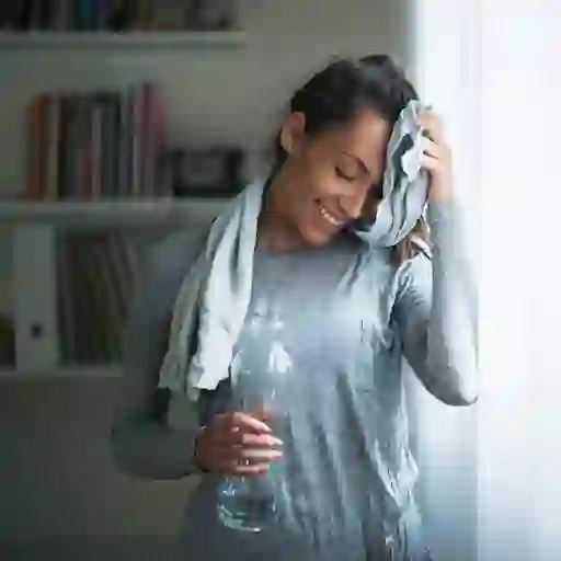 一位微笑的妇女在家中锻炼后用毛巾擦去额头上的汗水