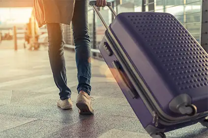 一个女人提着行李箱穿过机场。