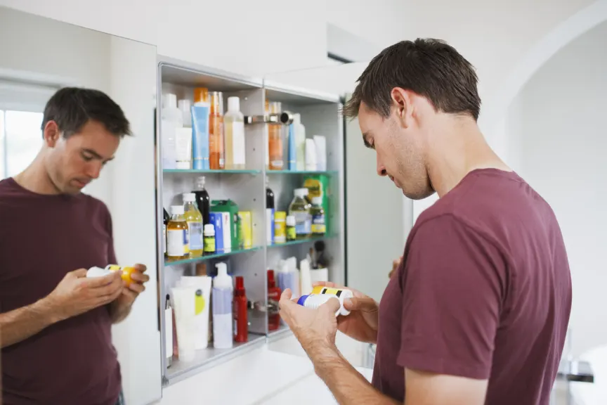 男子在浴室橱柜里凝视着药瓶。