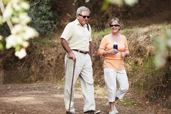 一位老人拄着拐杖走在外面。