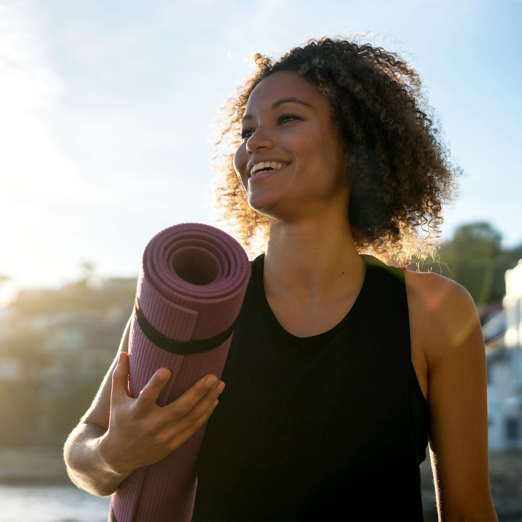 一名女子微笑着拿着瑜伽垫
