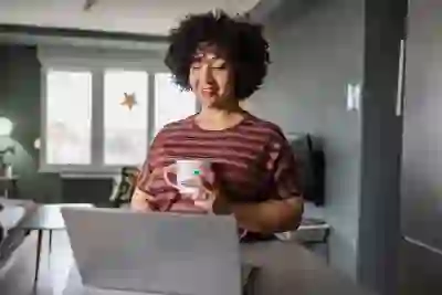 在家里的笔记本电脑上微笑的女人喝杯咖啡