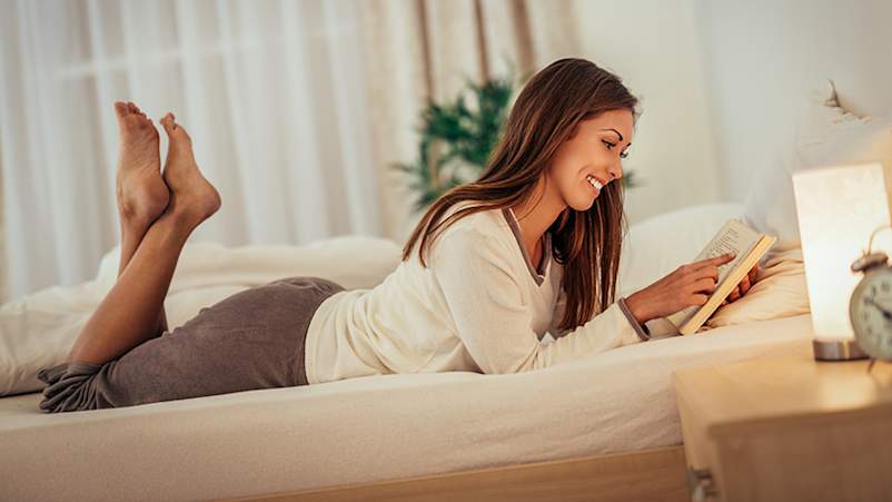 女人读一本书,晚上在床上。