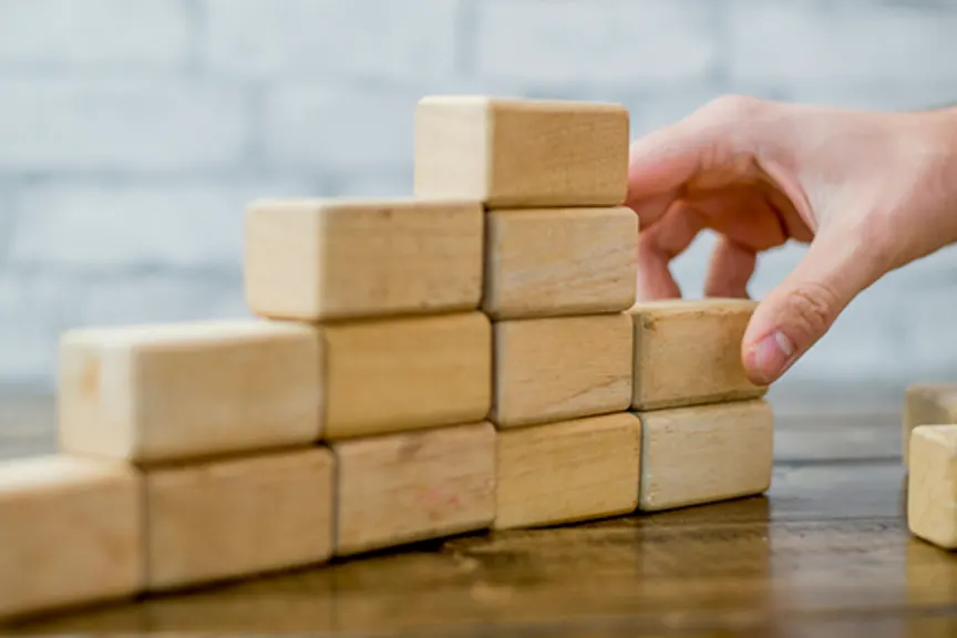 Woman building a structure with wooden building blocks.