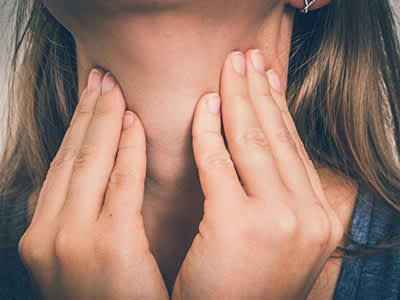 一个喉咙痛的女人正捂着她的喉咙。