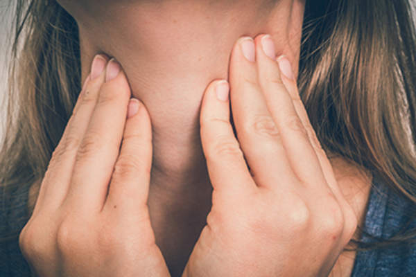 一个喉咙痛的女人正捂着她的喉咙。