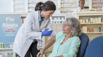 在药房接受流感疫苗注射的年长女性。