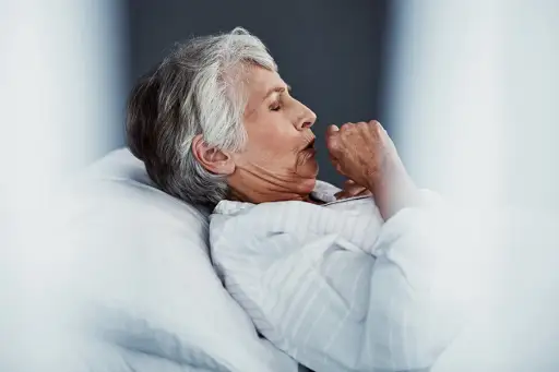 Senior woman coughing in bed