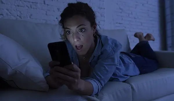 女人躺在沙发上使用手机互联网