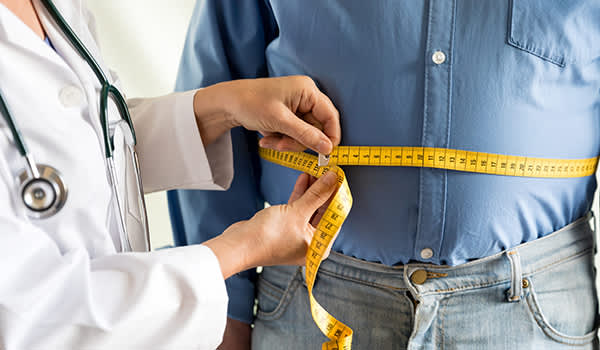 医生测量超重的男人的腰围。