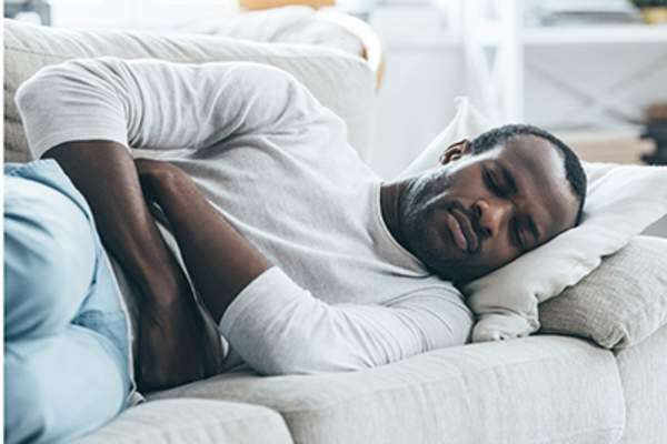 一名男子躺在沙发上,胃痛。