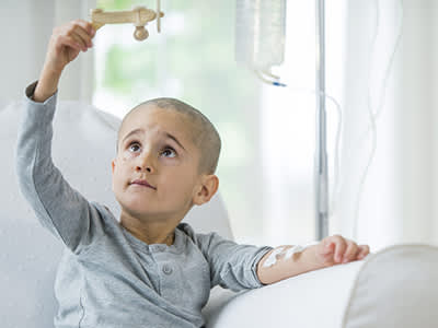 小男孩在化疗时玩木飞机。