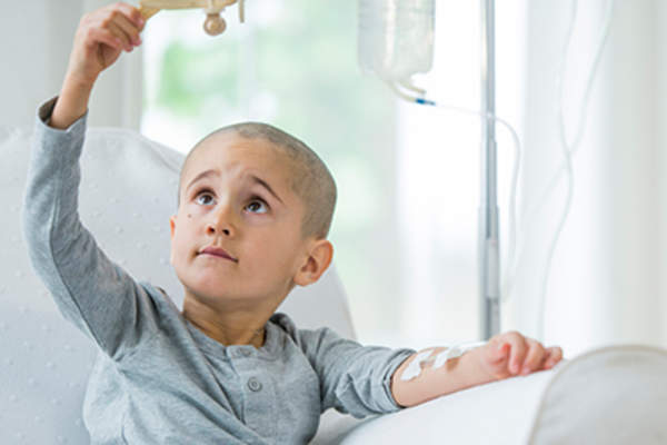 小男孩在化疗时玩木飞机。