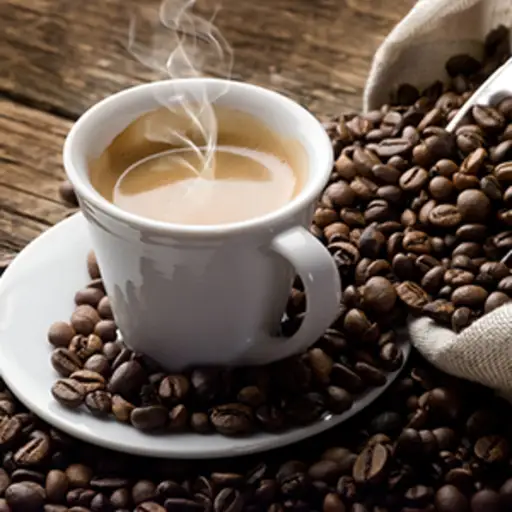 A steaming mug of hot coffee sits on a pile of coffee beans.